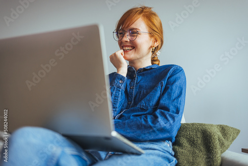 Happy businesswoman professional worker working online doing job on laptop at sofa, smiling female employee executive typing message using corporate computer software for business in modern office