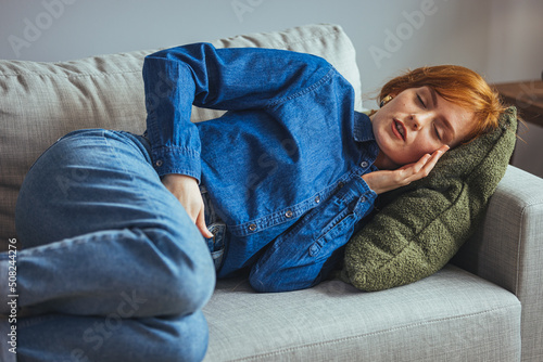 Young beautiful woman feel menstrual cramps and stomachache after menstruation.Hand holding stomach and belly after taking a medication.Problem and disorder of female body.