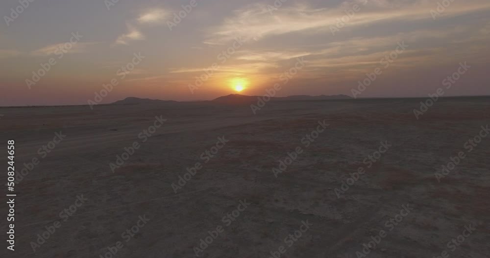 Flying away fast from a sunset on a flat salt plain in the deserts of Rajasthan in India Flying away fast from a sunset on a flat salt plain in the deserts of Rajasthan in India