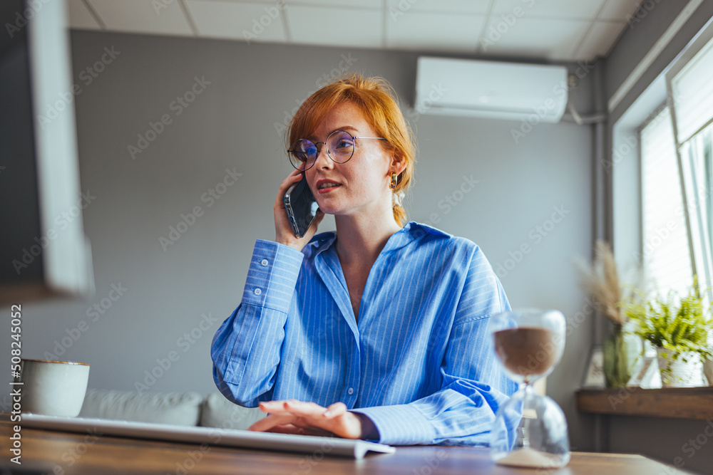 Beautiful young businesswoman having business call in office, her workplace, writing down some information. Woman talking on mobile phone, asking questions, looking at pc screen. Beautiful young businesswoman having business call in office, her workplace, writing down some information. Woman talking on mobile phone, asking questions, looking at pc screen.