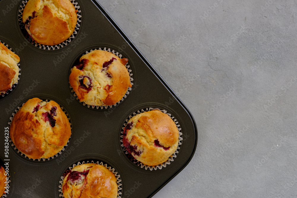 Fragrant lemon muffins with cherry in the form for baking on a gray background Fragrant lemon muffins with cherry in the form for baking on a gray background