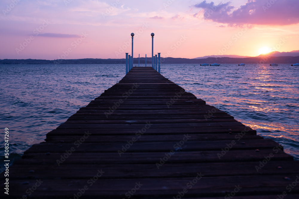 Obraz premium Landing stage with bathing ladder in sirmione on lake garda at sunset.