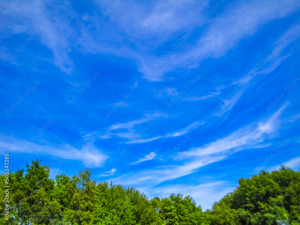 Blue sky with chemical clouds chemtrails on sunny day Germany.