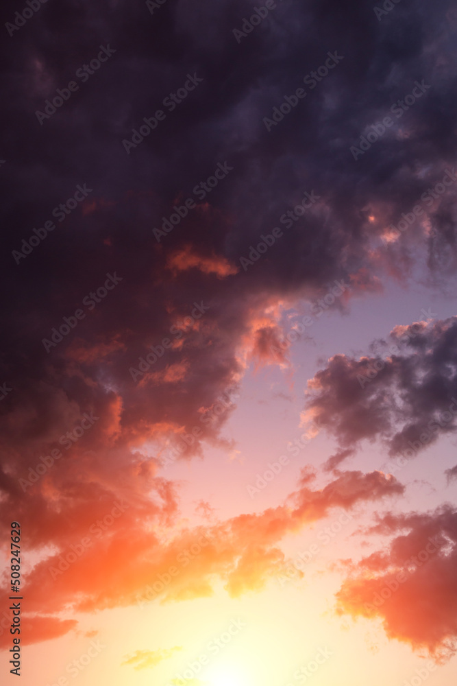 Epic dramatic sunset, sunrise on storm sky with dark clouds, orange yellow sun and sunlight