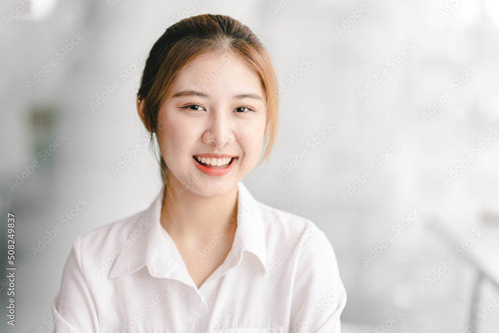 Attractive cheerful young female employee looks at the camera.