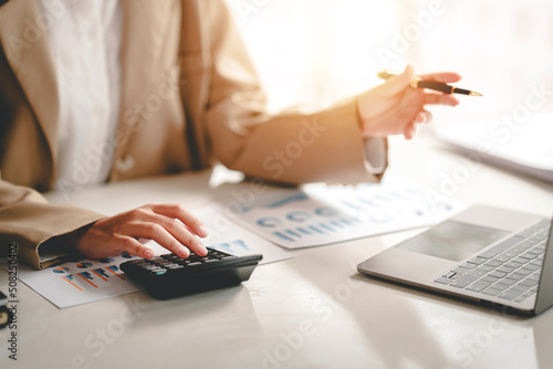 business woman or accountant who are using a calculator to calculate business data Accounting documents and laptop computer at the office business idea