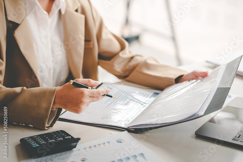 business woman or accountant who are using a calculator to calculate business data Accounting documents and laptop computer at the office business idea