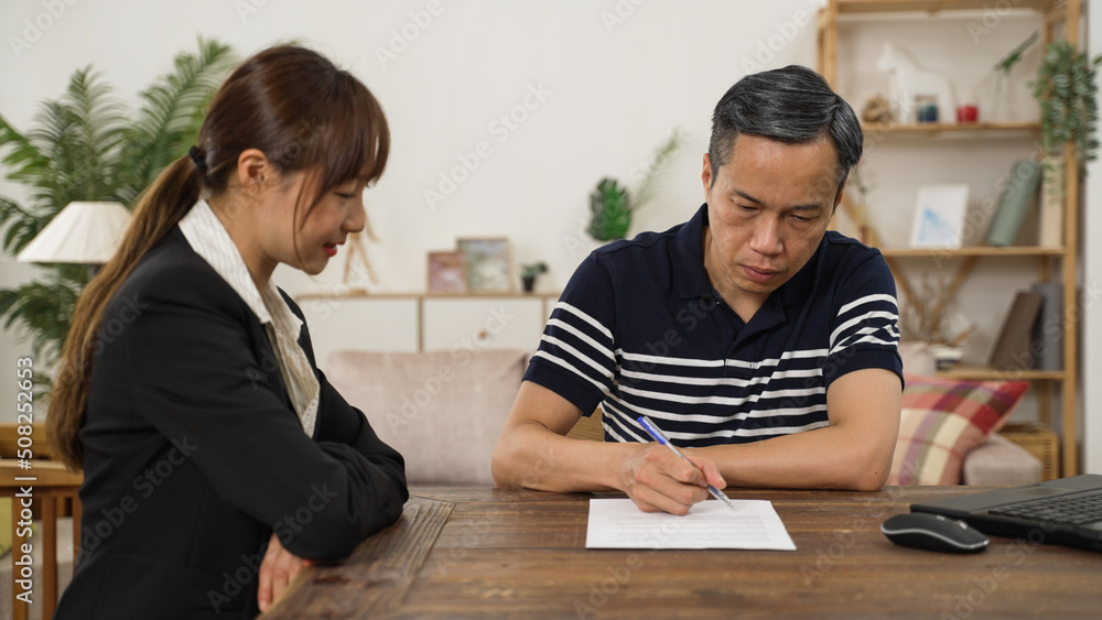 elderly man client putting signature on his disability insurance document after consultation at home. the female agent thanks him for the trust elderly man client putting signature on his disability insurance document after consultation at home. the female agent thanks him for the trust
