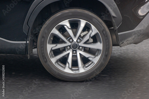 Rotating wheel of a car driving on the road, close up view