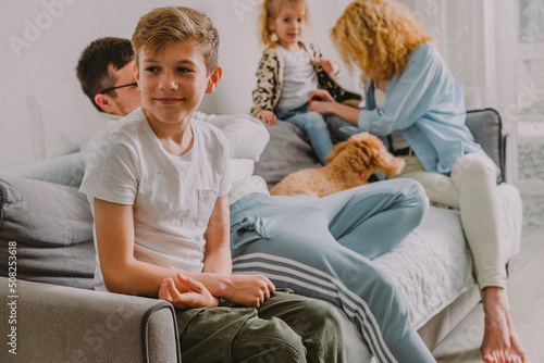 the concept of the appearance of the youngest child in the family. Close-up portrait of a teenage boy against the background of communication between dad and mom with a younger sister