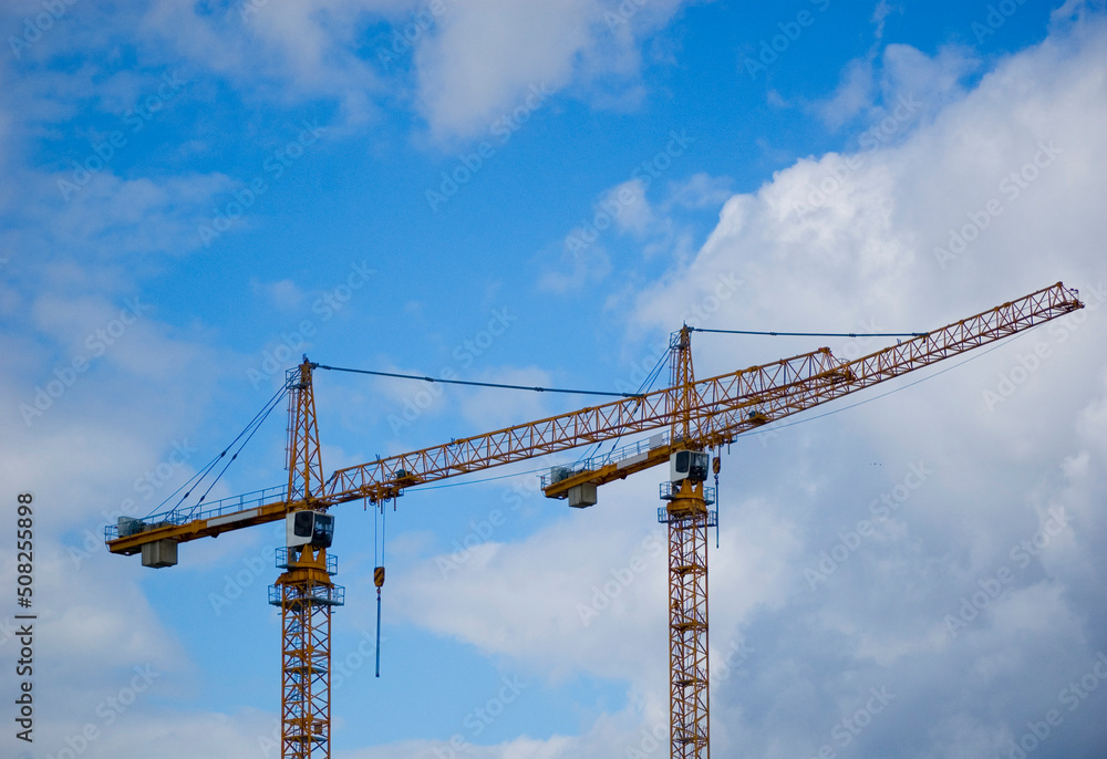 Large construction site crane working on a building complex with cloudy sky.