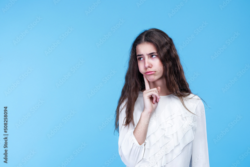 Young teenage girl wondering what happened, studio blue background Young teenage girl wondering what happened, studio blue background