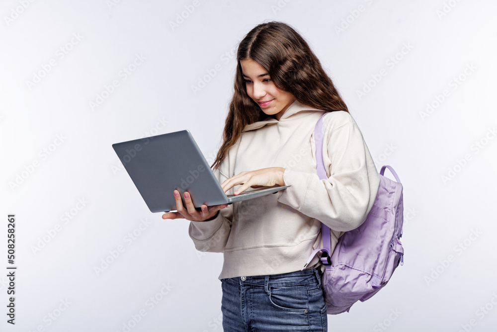 Teenage girl looking at her laptop, getting ready for school and finishing homework