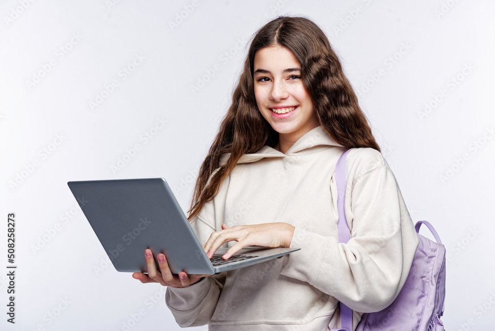 Naklejka premium Teenage girl looking at her laptop, getting ready for school and finishing homework