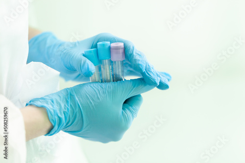 a nurse holds empty test tubes in two hands, preparing to take blood from a patient