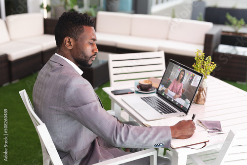 African american businessman planning work while video chatting with businesswoman on laptop