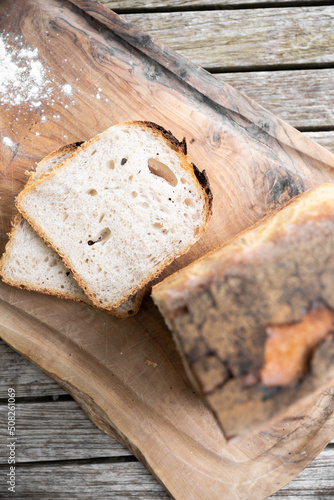 white tin bread loaf and slices on olive wood chopping board