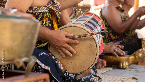 A musician plays a kendhang or ketipung, a traditional Balinese instrument, as part of a musical ensemble or gamelan, during a performance