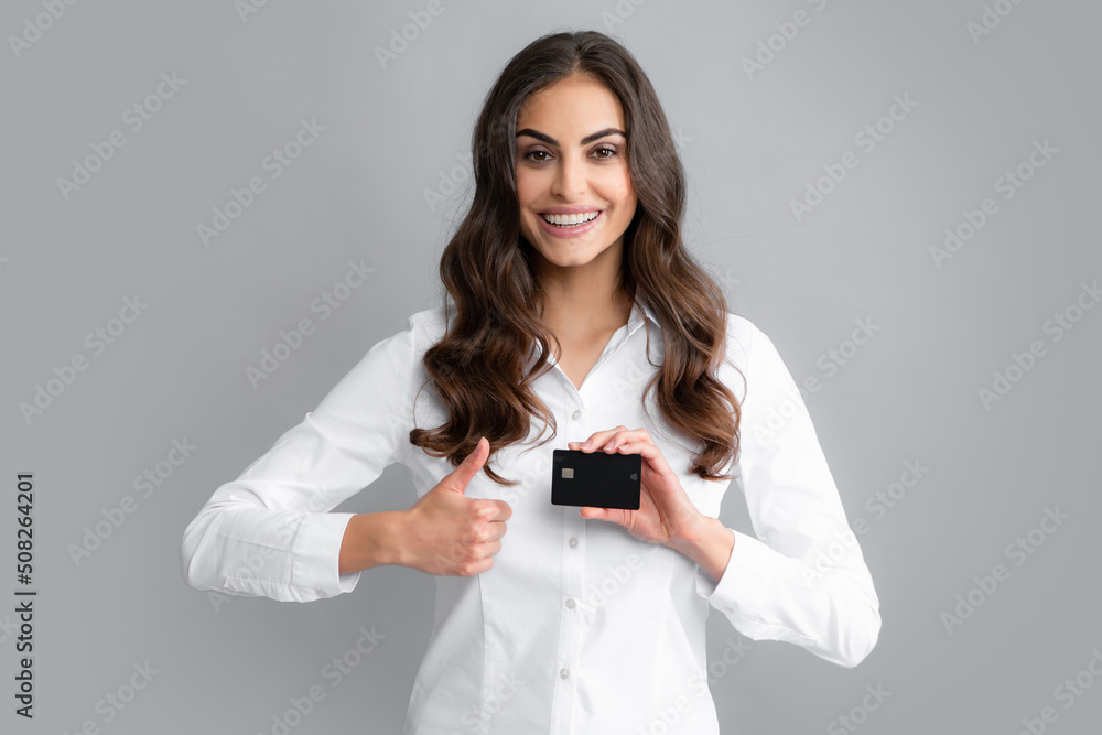 Portrait of a happy young girl showing plastic credit card isolated over grey background. Bank card, finance and banking concept. Portrait of a happy young girl showing plastic credit card isolated over grey background. Bank card, finance and banking concept.