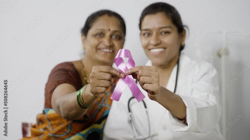 rack focus shot of doctor and patient showing breast cancer symbol by looking at camera - concept of healthcare, cure and awareness rack focus shot of doctor and patient showing breast cancer symbol by looking at camera - concept of healthcare, cure and awareness