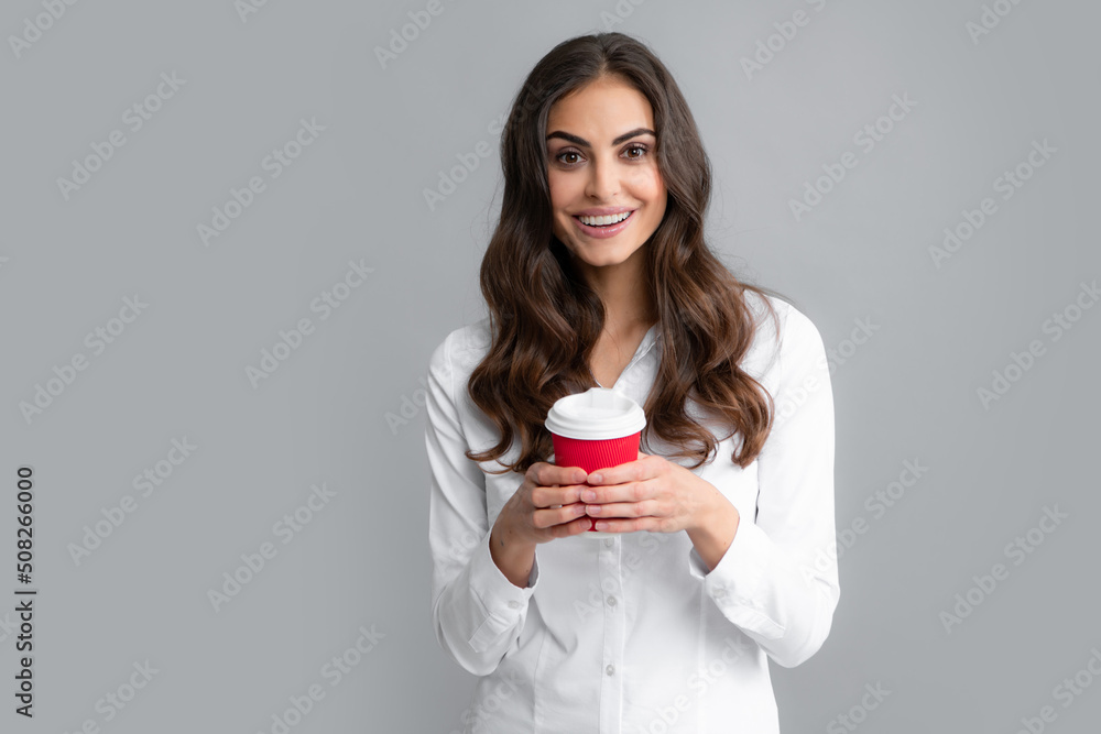 Beautiful woman in studio holding cup of coffee. Photo of cheerful positive pretty girlf holding mug of coffee smiling toothily isolated over gray background. Beautiful woman in studio holding cup of coffee. Photo of cheerful positive pretty girlf holding mug of coffee smiling toothily isolated over gray background.