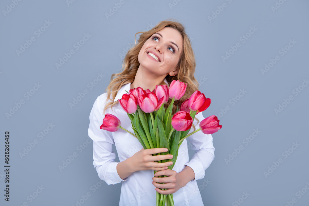 dreamy blonde woman with spring tulip flowers on grey background dreamy blonde woman with spring tulip flowers on grey background