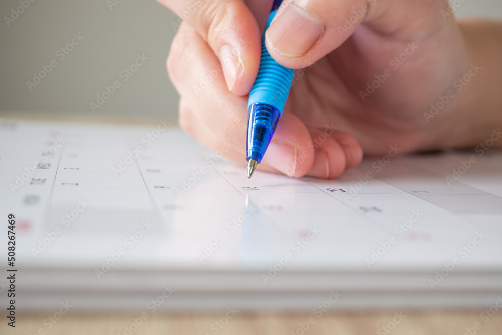 Woman hand with pen writing on calendar date business planning appointment meeting concept Woman hand with pen writing on calendar date business planning appointment meeting concept