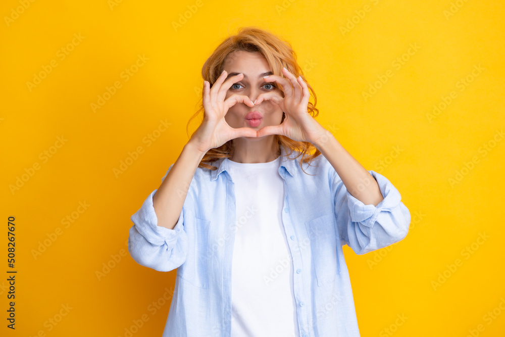 Pretty romantic young woman making a heart gesture, showing love and affection grateful gesture with a happy tender smile. Girl feelings love. Lovely woman with heart sign symbol. Pretty romantic young woman making a heart gesture, showing love and affection grateful gesture with a happy tender smile. Girl feelings love. Lovely woman with heart sign symbol.