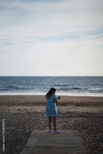 mujer de espaldas tomando fotos en la playa sobre camino de madera  © MiguelAngelJunquera