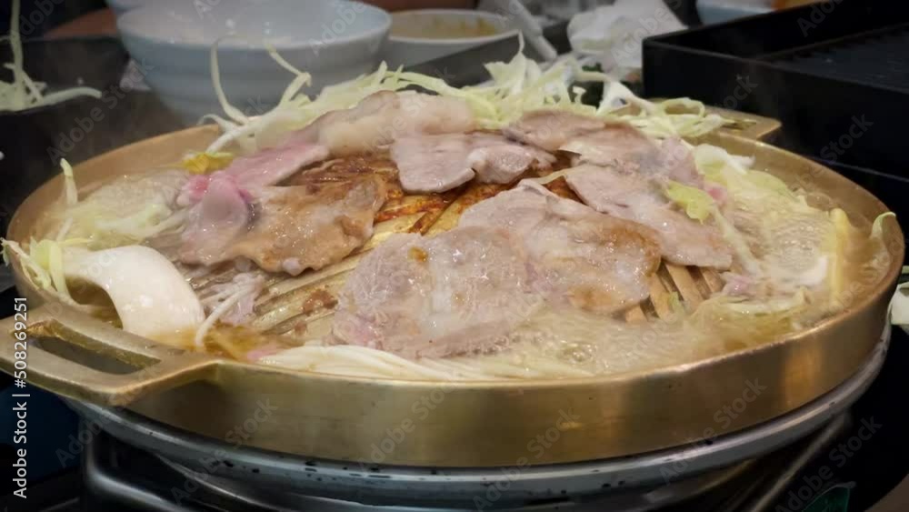 Chopsticks are used to keep raw fresh pork slices on a brass pan from sticking together. In a Thai restaurant, there is an Asian-style BBQ. Chopsticks are used to keep raw fresh pork slices on a brass pan from sticking together. In a Thai restaurant, there is an Asian-style BBQ.
