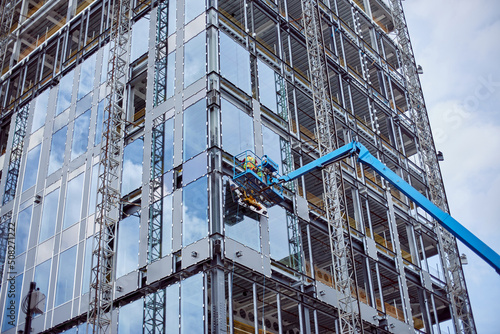 Installation of double-glazed windows from a crane, on a high-rise building. Construction of a skyscraper. Installation of windows on the glass building facade.