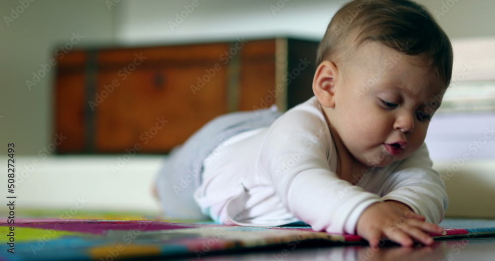 Cute baby lying on floor touching play carpet Cute baby lying on floor touching play carpet