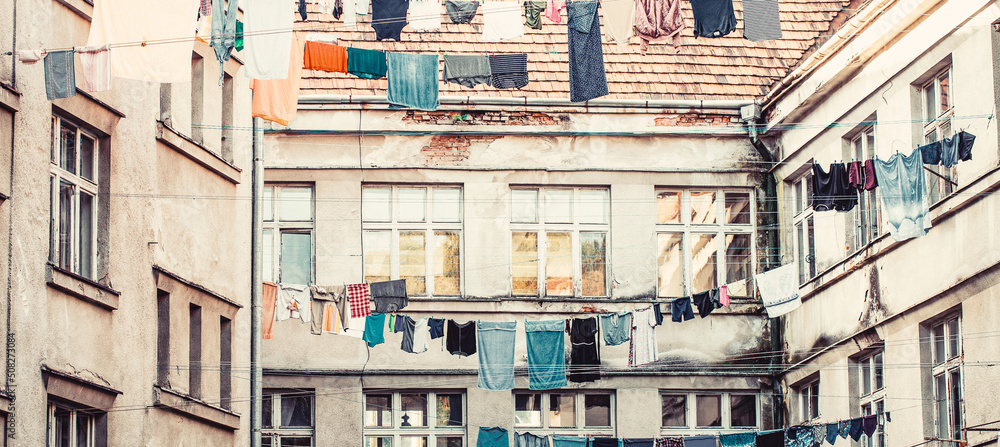 Washed clothes drying outside of an old house. Washed clothes drying. Fresh clean clothes are drying outside. Clothes hanging to dry on a clothes-line. Laundry dryings on the rope