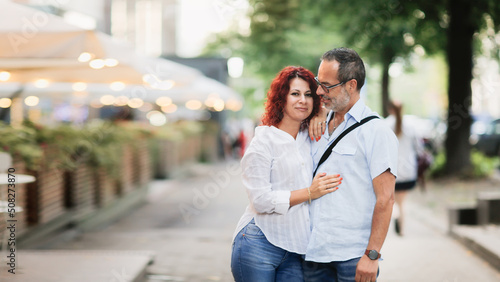 Cute European middle-aged couple hold hands and walk through the streets of the city,, summer walks and travel