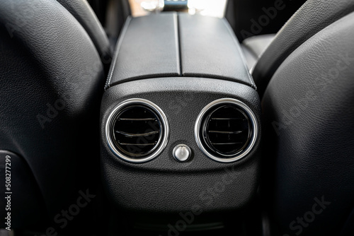 Фотография The interior of a modern passenger car with visible two round air inlets in the armrest at the rear