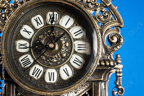 dial of vintage bronze clock, antique clock photo close up, old bronze clock in gilding, front of bronze fireplace clock