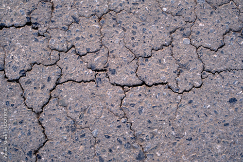 Old worn and cracked asphalt with cracks. Asphalt cracked road dark texture.