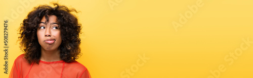 discouraged african american woman looking away isolated on yellow, banner.