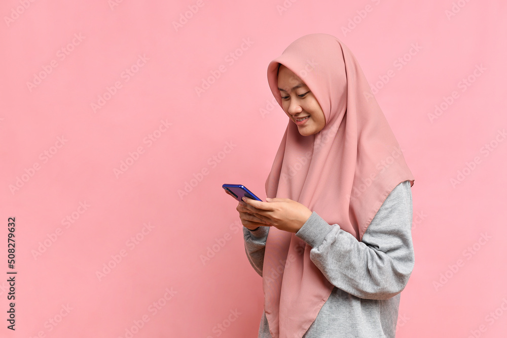 Happy Smiling Asian Muslim woman typing on cellphone Happy Smiling Asian Muslim woman typing on cellphone