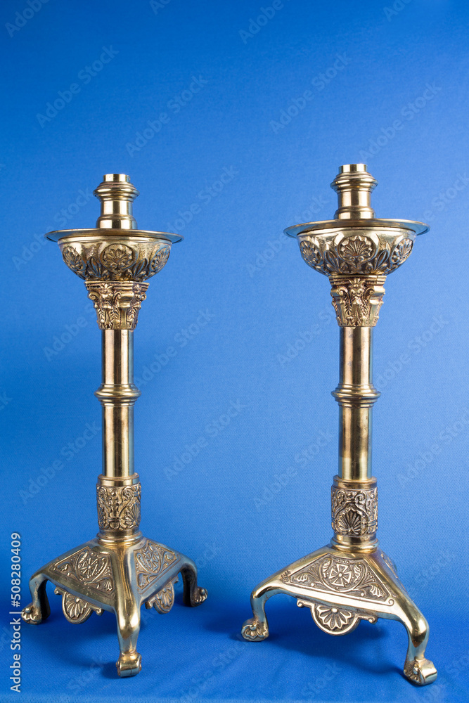 two classic bronze chandelier on a blue background, ancient candlesticks studio photo, antique candlesticks isolated, brass candelabra, vintage candlesticks vertical photo