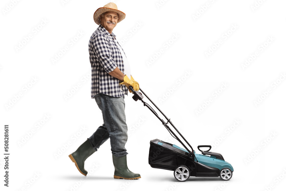 Full length profile shot of a mature man with a straw hat and boots using a lawn mower - obrazy, fototapety, plakaty 