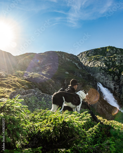 Farmer and his dog near a waterfall in the moutains