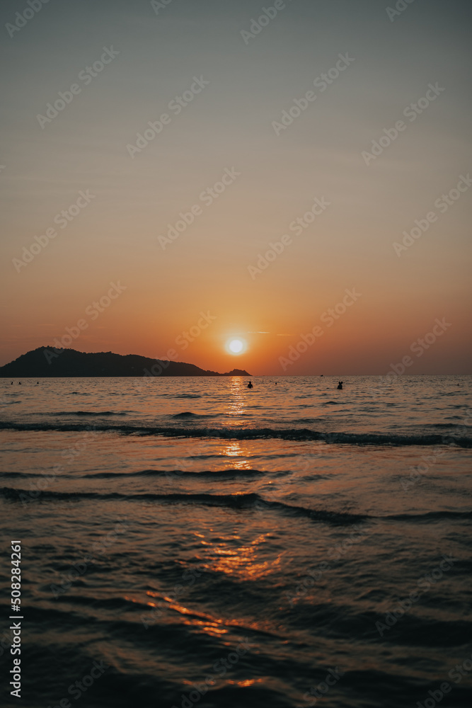 Sunset glowing in the waves of a beach in Phuket, thailand