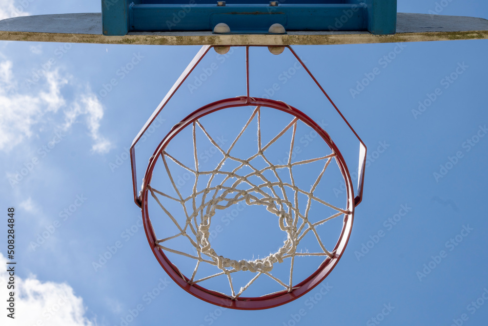 Close-up of a basketball hoop seen from below, blue sky in the background Close-up of a basketball hoop seen from below, blue sky in the background