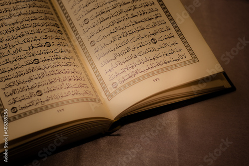 Al-Quran is a holy book of Islamic guidance isolated. religion concept. open a page of the Quran on a wooden prayer mat open page of Quran.
