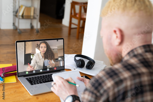 Albino african american businessman noting during video call with biracial female colleague