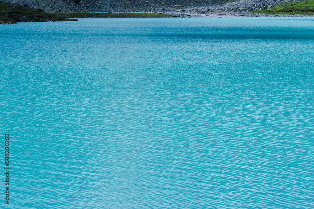 Turquoise water of mountain lake as background. Blue river with ripples and reflection