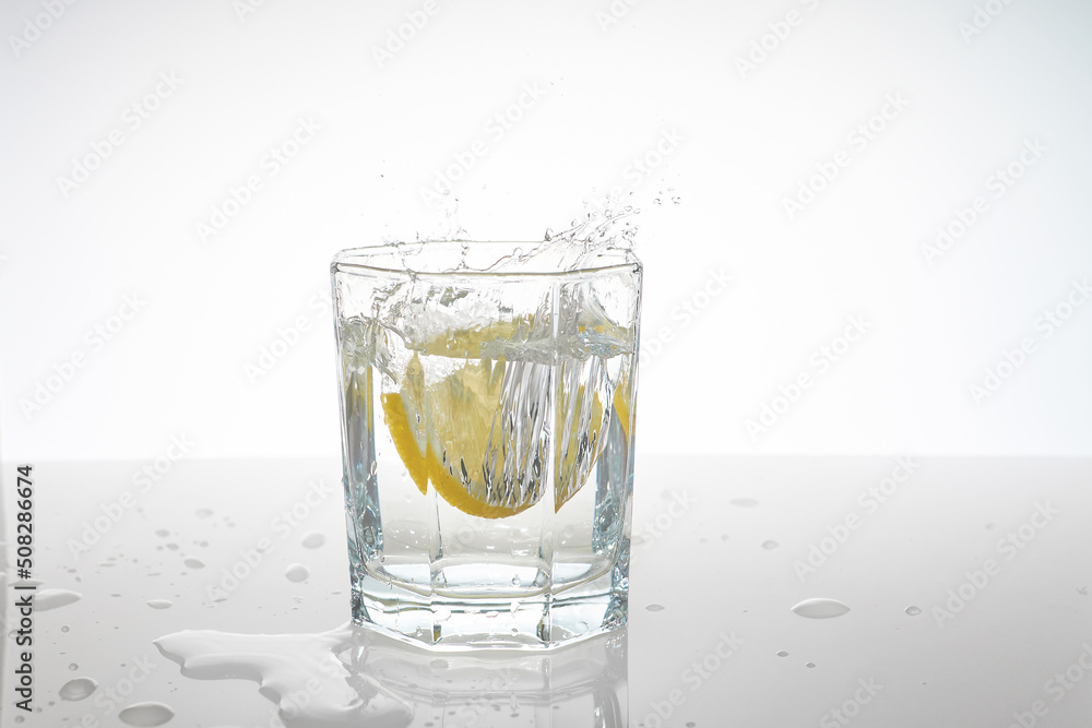 water splashes in a glass from falling lemon slices into it water splashes in a glass from falling lemon slices into it