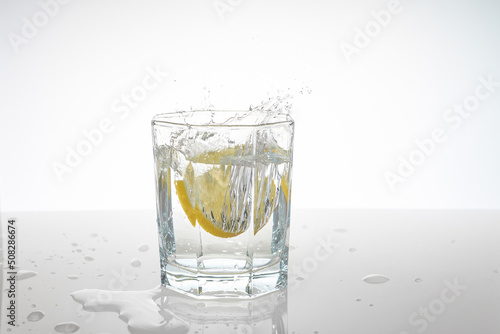 water splashes in a glass from falling lemon slices into it