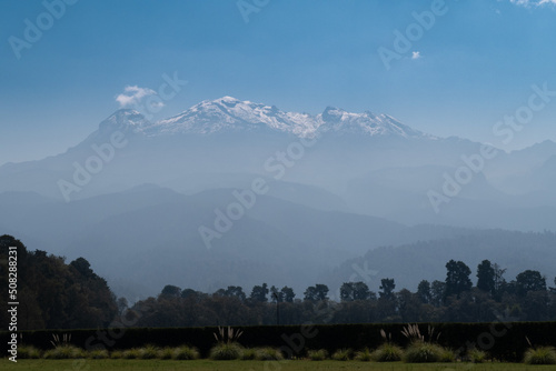 imagen cerrada de volcán iztaccihuatl con nieve, árboles y barda en primer plano, tomada en amecameca estado de méxico photo